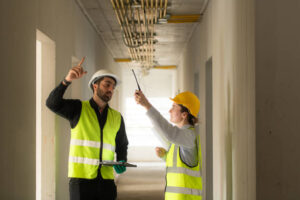 Male and female engineers working on construction site, they are monitoring the building's electrical system.